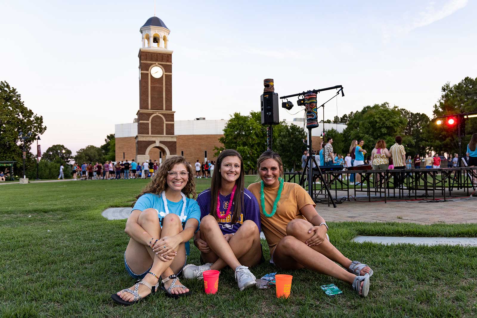 three students sitting on ground outside