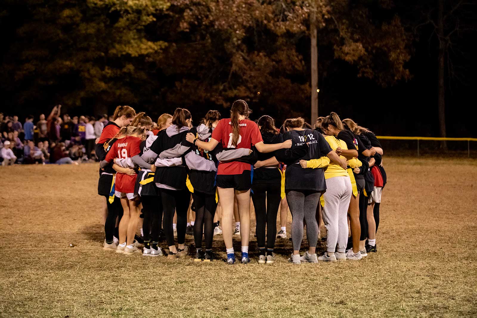 female students praying before flag football game