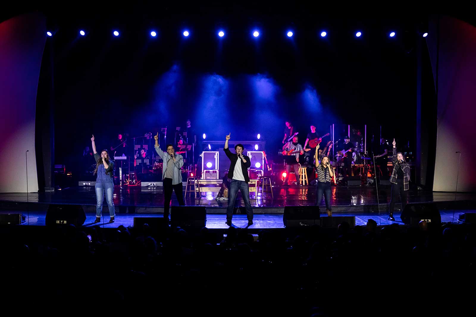 band performing on stage with raised hands